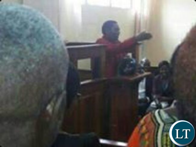 Hakainde Hichilema gestures the UPND symbol in the dock