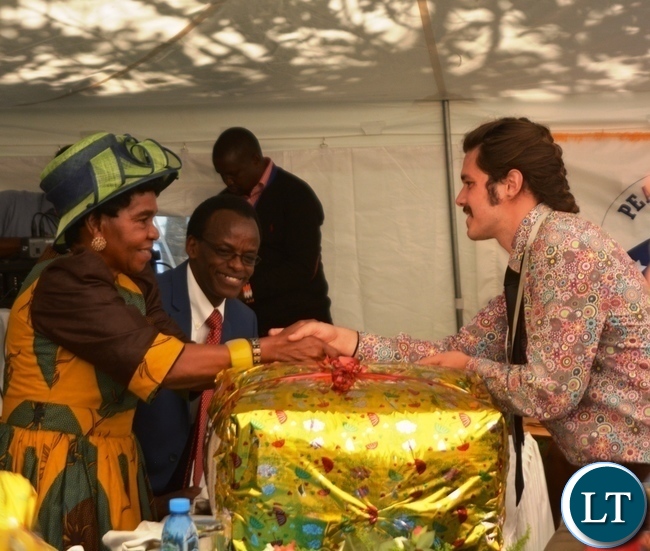 Peace Corp Volunteer Dylon Scott Taylor(r) presents a gift of appreciation to Her Royal Highness Senior Chieftainess Nkomeshya Mukamambo II(l) at the Peace Corps Swearing in Ceremony for Environment and Aqua-Culture Volunteers in Lusaka