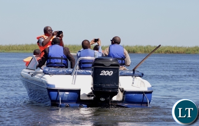 Zimbabwean Energy Permanent Secretary Patson Mbiri (standing) taking photos of the Zambezi River water levels during the tour of Matongo Platform, a Hydrometric Station on the Barotse Flood Plain in Mongu