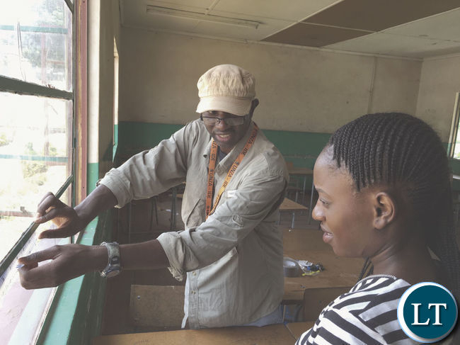 Dr Samuel Mutiti shows his research assistant how to collect dust samples from a school window in Kabwe, Zambia Dr Samuel Mutiti shows his research assistant how to collect dust samples from a school window in Kabwe, Zambia