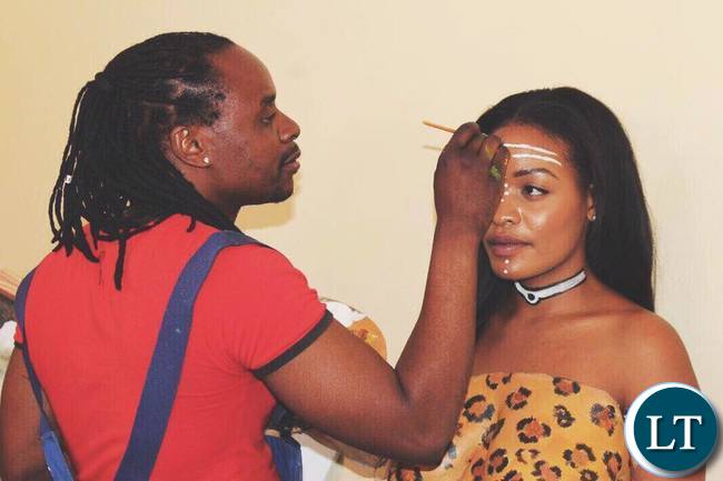 Artist Caleb Chisha working on Iris Kaingu's body art