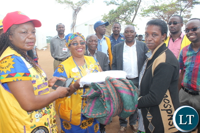 Lions Club Governor for District 413 Zambia, Ms Jess ica Choobe, handing over the donated materials to the refugee leader at Kenani refugee transit centre.
