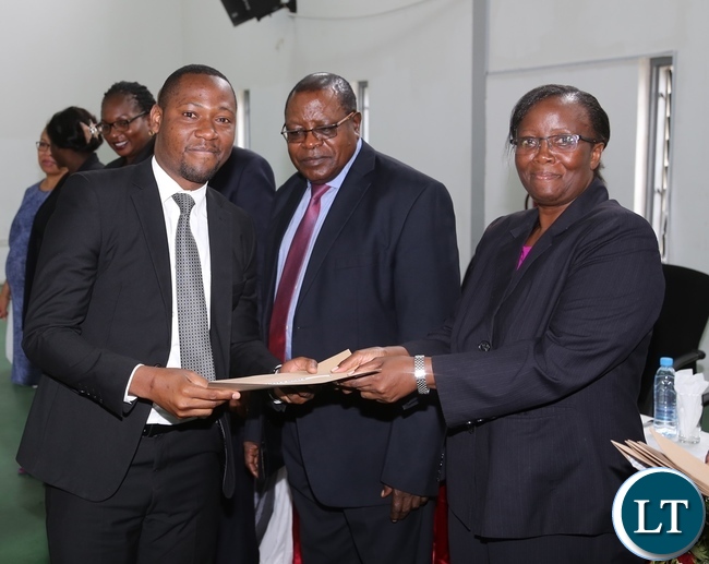 Zambia Institute of Advanced Legal Education (ZIALE) Lecturer Doris Mwiinga presents the post-graduate diploma in legislative drafting to Moses Lupiya during the graduation ceremony Zambia Institute of Advanced Legal Education (ZIALE) Lecturer Doris Mwiinga presents the post-graduate diploma in legislative drafting to Moses Lupiya during the graduation ceremony