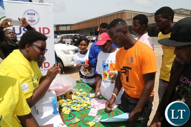 Mercy Bulaya explains on how to use the condom to people during the International Condom Day tour of stands at Central Mall
