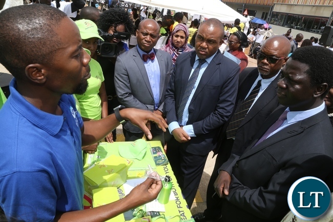 Stand exhibitor explains to Ministry of Health Director Public Health Dr. Andrew Silumesii during the International Condom Day tour of stands at Central Mall