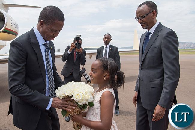 President Edgar Lungu receives a bouquet of flowers from a young girl on arrival at the Kigali International Airport, as his host, President Kagame, looks on yesterday. (Village Urugwiro)
