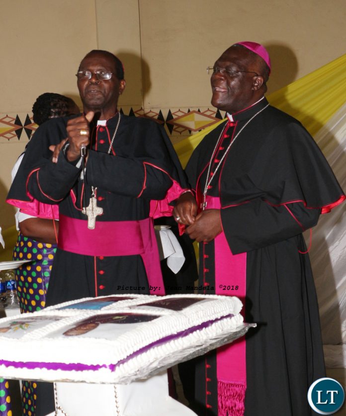 Bishop Telesphore George Mpundu and Bishop Alick Banda cutting a cake.