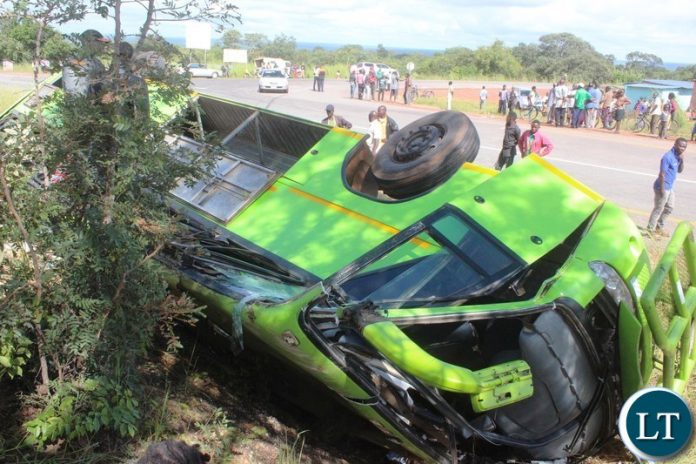 Onlookers catch a glimpse of lusaka bound Juldan coach Reg. No ABE 6940 which has claimed 4 lives after over turning due to allegedly failure by the driver to stop on the T-Junction along the Kasama- Luwingu road in the early hours of Monday. The driver is among the 3 men who died on the spot while one female died upon arrival at the Hospital.-Picture by Mary Bwembya (ZANIS).