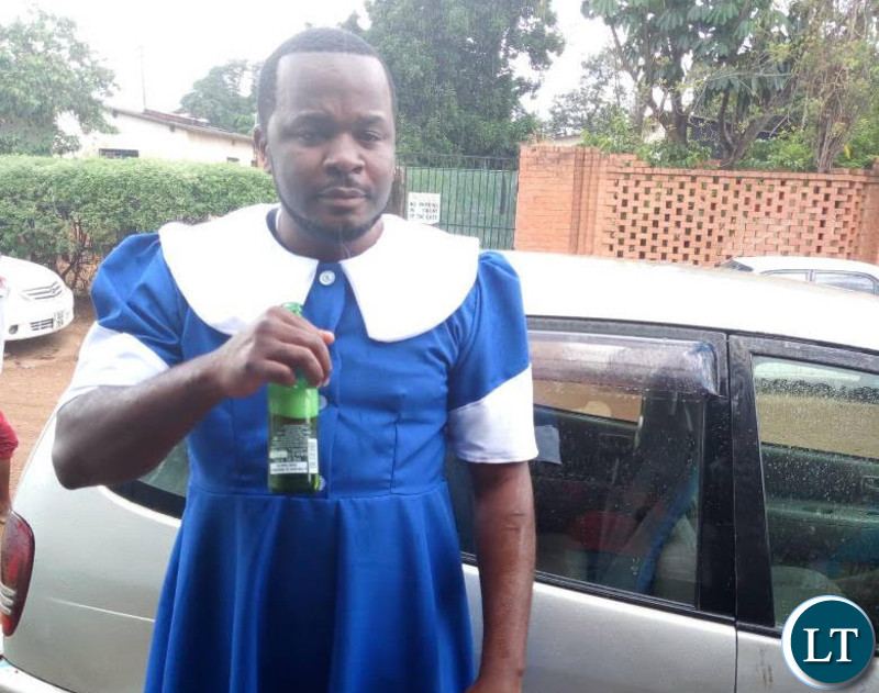 Maxwell Chongu clad in a Seventh Day Adventist (SDA) Dorcas uniform while holding a bottle of beer.