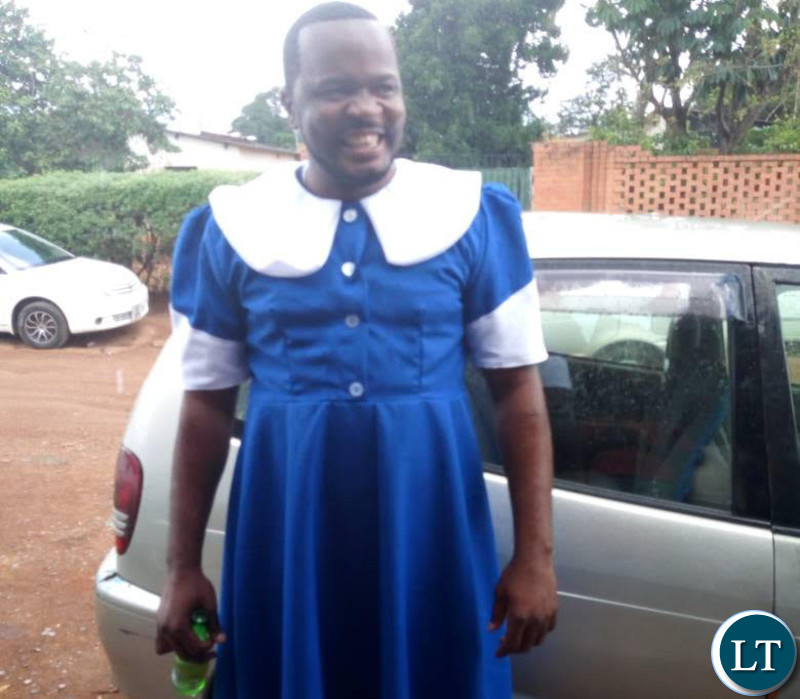 Maxwell Chongu clad in a Seventh Day Adventist (SDA) Dorcas uniform while holding a bottle of beer.