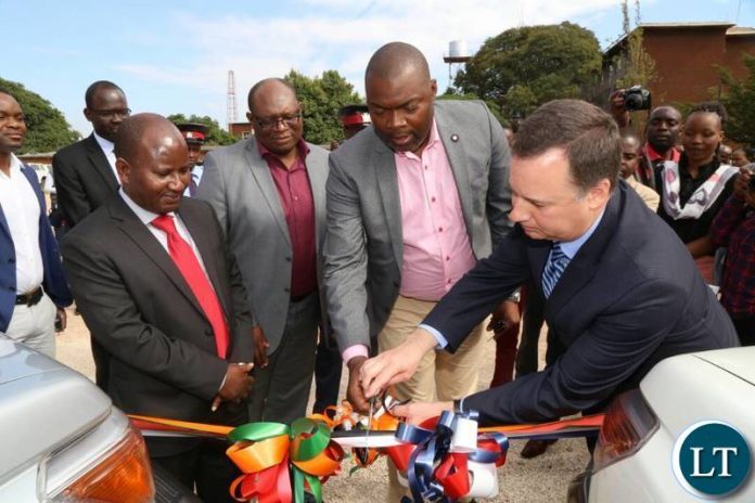 Lusaka Province Minister Bowman Lusambo cuts a ribbon during the hand over of the vehicles