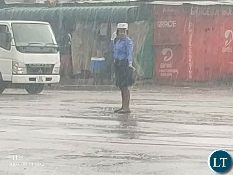 Traffic Police Officer Charity Nanyangwe controlling traffic in heavy rains without safety attire and rain coat
