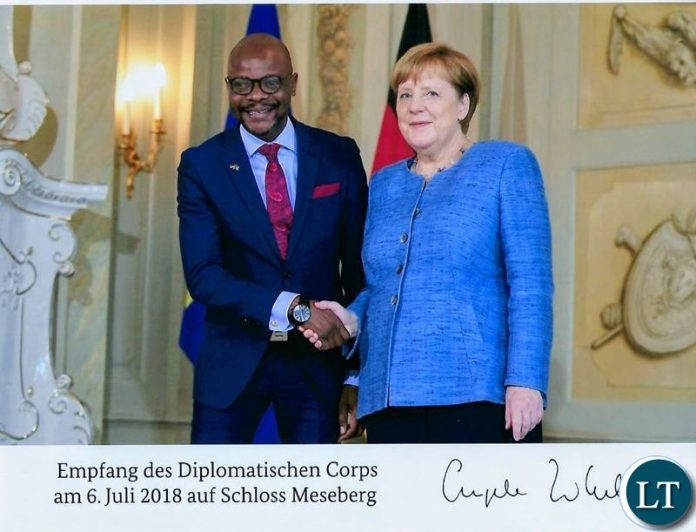 Images, chancellor Merkel shakes hands with Zambia Ambassador Mukwita,