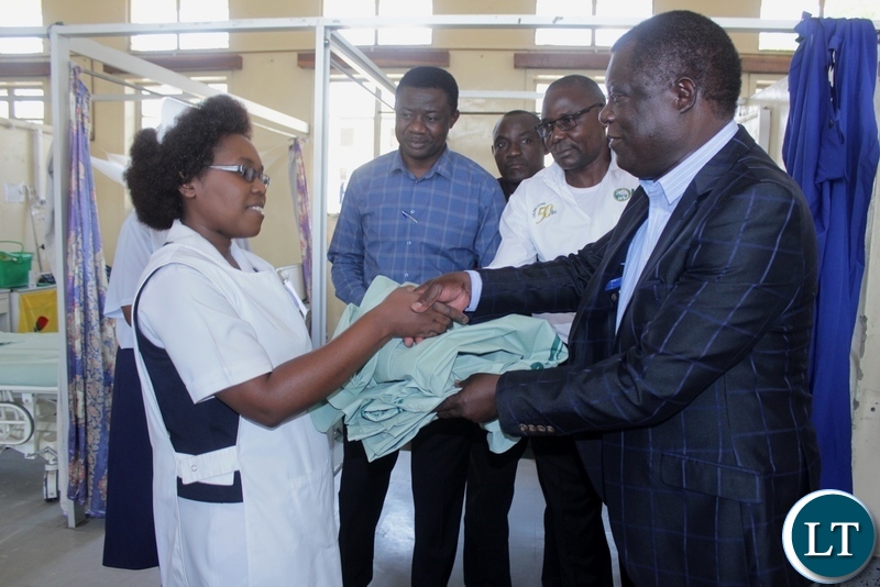 Mongu District Commissioner Susiku Kamona (r) hands over linen to Nurse in-Charge Female Ward Christine Mwendabai (l) as ZSIC-LIFE Regional Manager Arnold Mbangu (2nd r) and Dr. Bimu Yakilembe (2nd l) look on during the donation of 40 linen to Lewanika General Hospital by ZSIC-LIFE to celebrate 50 years, in Mongu