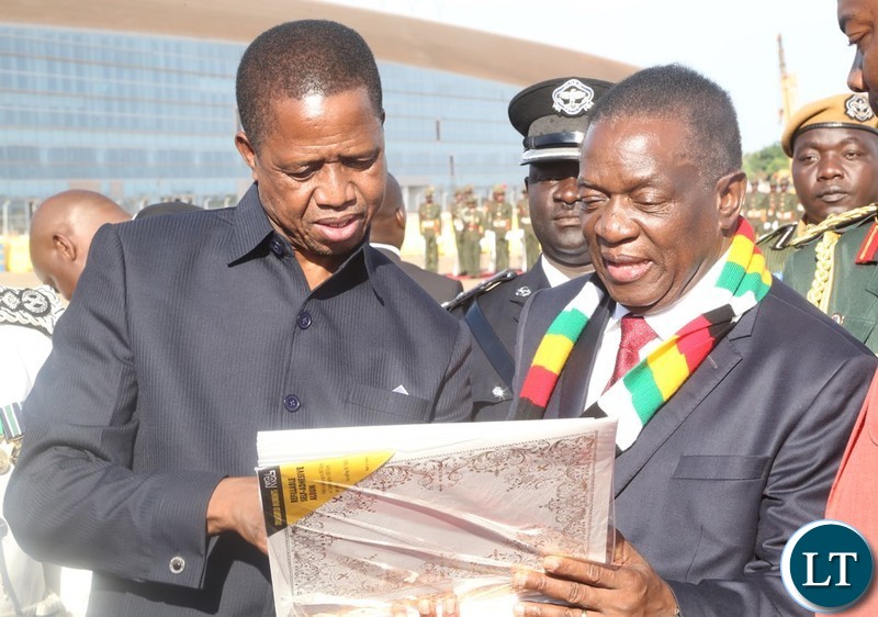 President Edgar Lungu shows pictures to President of Zimbabwe Emmerson Dambudza Mnangagwa shortly before handing over the Presidential photo album to him at Kenneth Kaunda International Airport before his departure