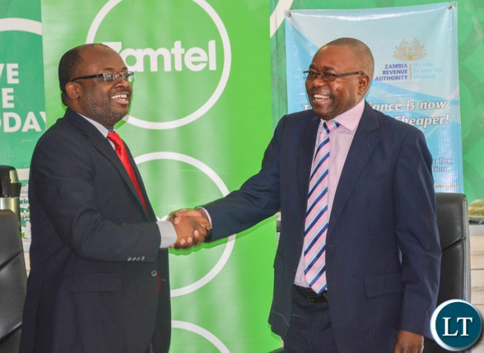 Zamtel CEO Mr Sydney Mupeta shakes hands with ZRA Commissioner General Mr Kingsley Chanda during a joint news briefing recently.