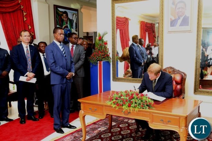 President Edgar Lungu looks on whilst Prince Harry the Duke of Sussex signs in the visitors book at State House shortly after the Prince called on the President