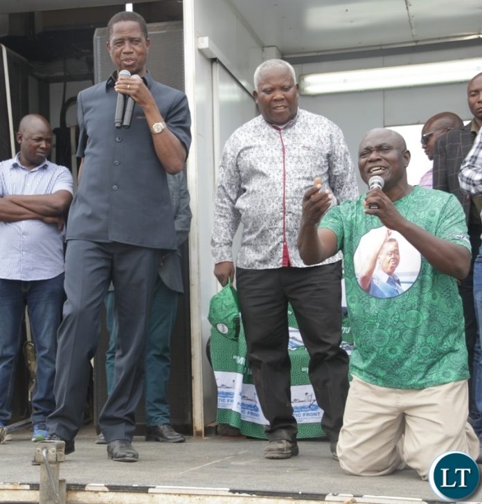 Lupososhi PF council Chairperson Candidate John Kandangala kneel to ask for votes as President Edgar Lungu looks on at a rally in Lupososhi District