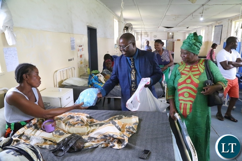 Bishop Joseph Ndashe flanked by his wife Dorothy Ndashe give Christmas gift to a patient Esther Zulu at Liteta Hospital during the giving of Christmas presents