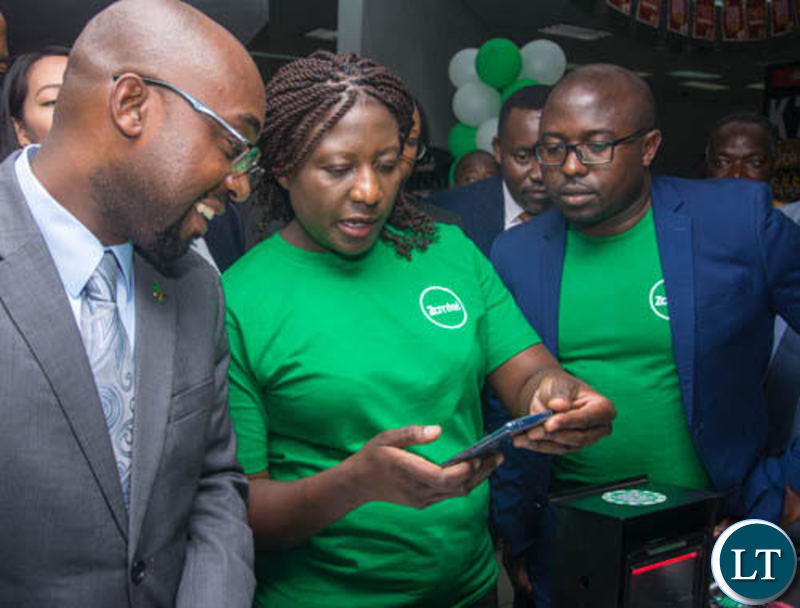 Transport and Communications Minister Brian Mushimba and Zamtel Acting Chief Information Officer Jason Mwanza look on as Zamtel Products Manager Mrs. Comfort Nyondo Mbulo demonstrates how ZamPay APP operates at Spar Arcades