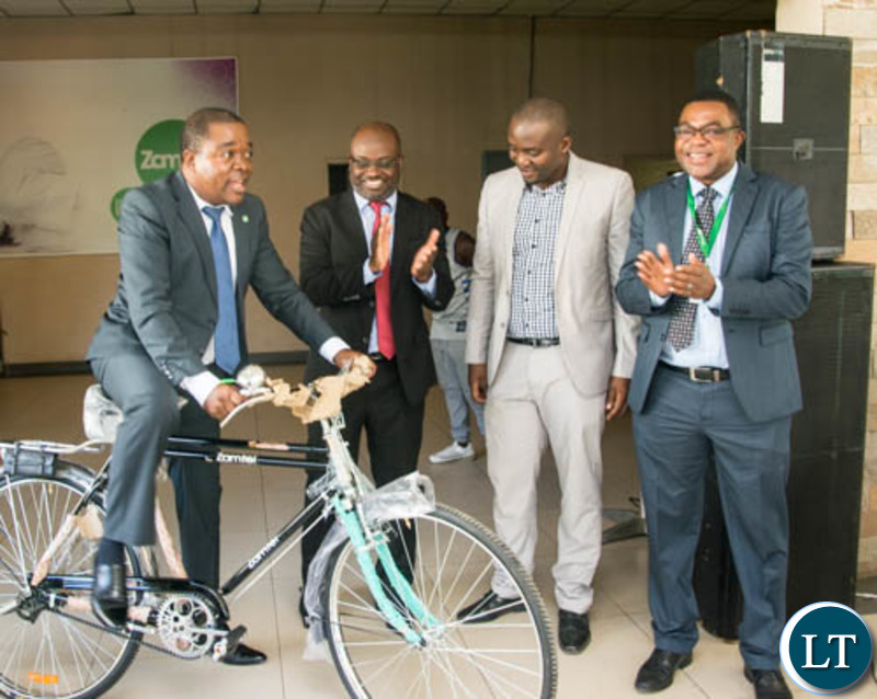 Transport and Commmunications Permanent Secretary Eng. Misheck Lungu tries out one of the bicycles during the hand over ceremony at Zamtel House