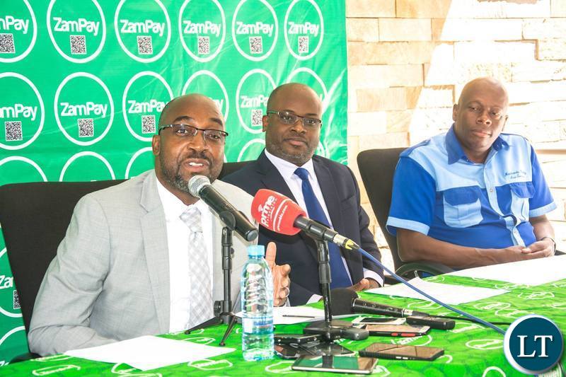 Transport and Communications Minister Brian Mushimba speaking during the launch of the ZamPay Number Neutral Capability as CEO Sydney Mupeta and Mazhandu Family Bus Services Director Justine Mazhandu look on.