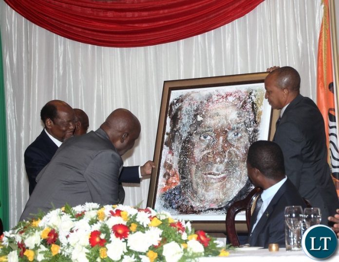 Mozambique former President Joaquim Chissano presenting a painting gift to Zambia 1st president Kenneth Kaunda on behalf of Africa Forum while looking are president Edgar Lungu and assistant to former Mozambique president Tomas de Sousa Mabuiangue