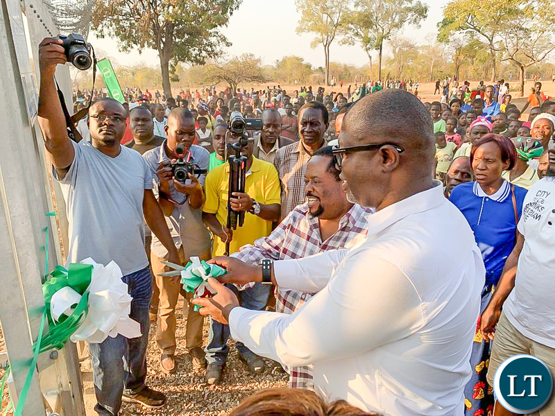 Msanzala Member of Parliament Peter Daka gets assistance in cutting a ribbon to symbolise the launch of a communication tower at Penja-Penja Village in Petauke