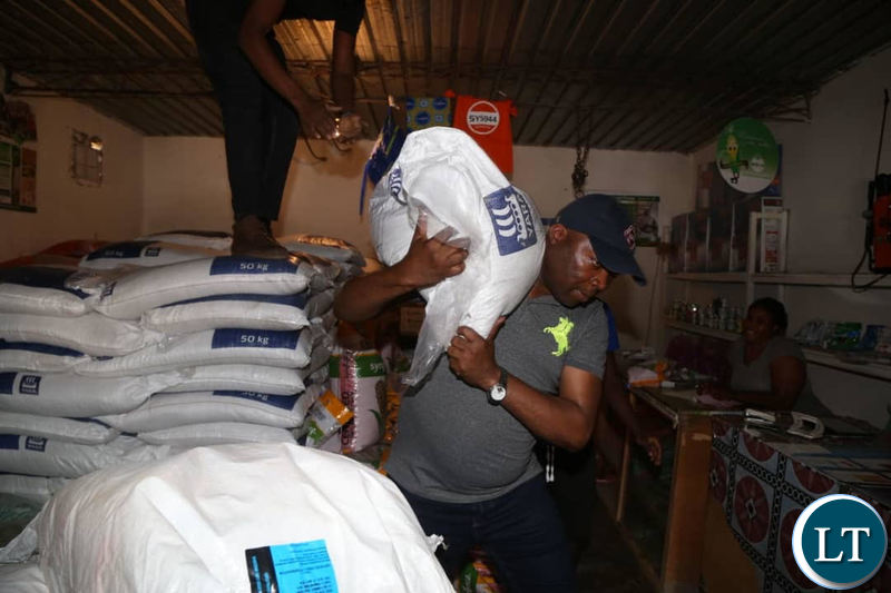 Lusaka Province Minister Bowman Lusambo helps in lifting a bag of Fertiliser during an inspection of some agro shops in Chongwe
