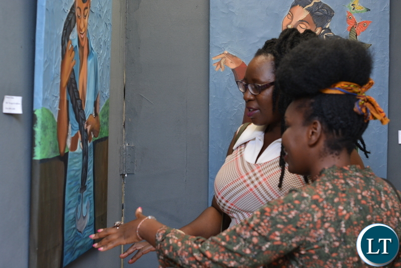 Jessie Chisi center with her husband far right, chats with Samba Yonga, at the one night only solo exhibition.