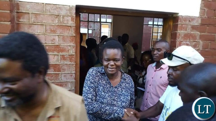 Laura Miti forces a smile as she greets sympathizers after leaving the court premises