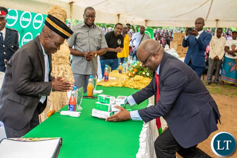 Zamtel CEO Sydney Mupeta hands over some low cost handsets to Chief Mukanya of the Kunda people of Mambwe District during the commissioning of the communications tower in the area