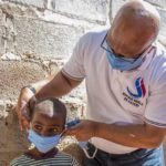 Nevers Mumba assisting a Child put on a face Mask