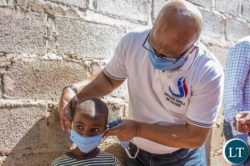 Nevers Mumba assisting a Child put on a face Mask