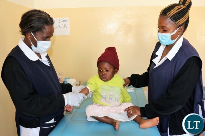 Nurses prepare a child for blood lead level testing
