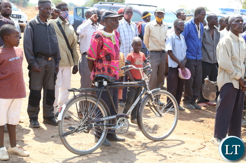 A beneficiary with a bicycle waits to receive the land title from the Vice President Inonge Wina during the handover cement, iron sheets and blocks to the flood and displaced victims in Mufuchani-Kitwe