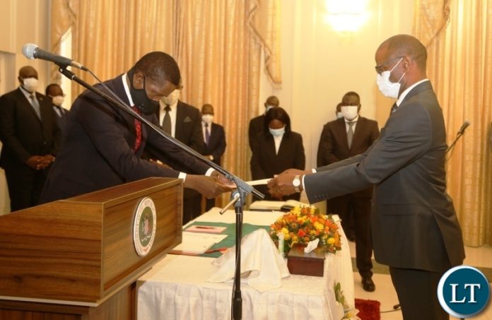President Edgar Lungu presents a letter of oath to newly appointed Bank of Zambia Governor Christopher Mvunga during swearing ceremony at State House
