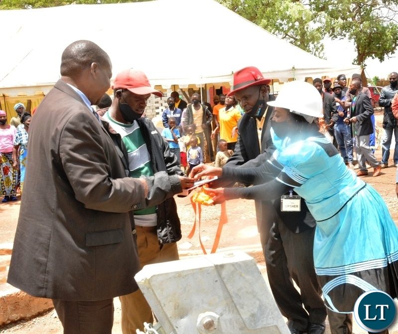 Ministry of Mines Director of Geological Survey Chipilauka Mukofu receive a borehole manual and keys from Kaiko Women's Club Chairperson Getrude Mundia on behalf of Kanyanja Community during the launch of Kaiko Women's Club Bore hole initiative in Shantumbu