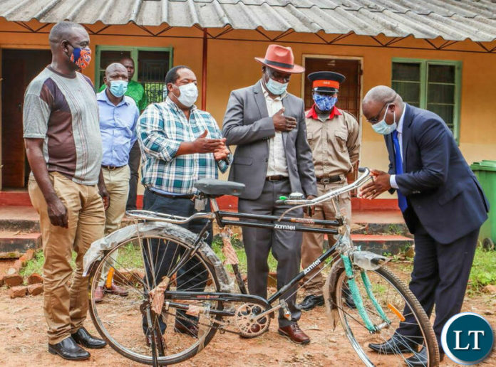 Zamtel CEO Sydney Mupeta hands over a bicycle to Chief Sandwe as Msanzala Member of Parliament Peter Daka looks on.