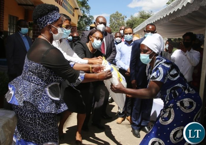 First Lady Esther Lungu hands over a food hamper donated by AFCON to Kizito Women Council Chairperson Mary Mukuka in Lusaka. Picture by SUNDAY BWALYA/ZANIS