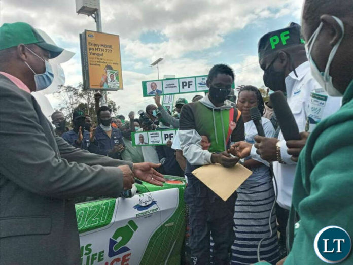 PF Member of the Central Commitee Paul Moonga witnesses as PF Luapula Parliamentary candidate Chanda Katotobwe hands over the keys to the vehicle to Mr Michael Mali