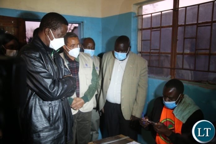 PRESIDENT Edgar Lungu having his details on the voter's card checked by Electoral officer at Andrew Mwenya polling station in Chawama