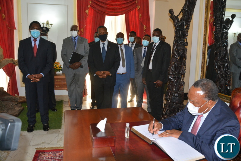 Former President of South Africa, Kgalema Motlanthe signing the Visitors' book at state house as President Hakainde Hichilema looks on.