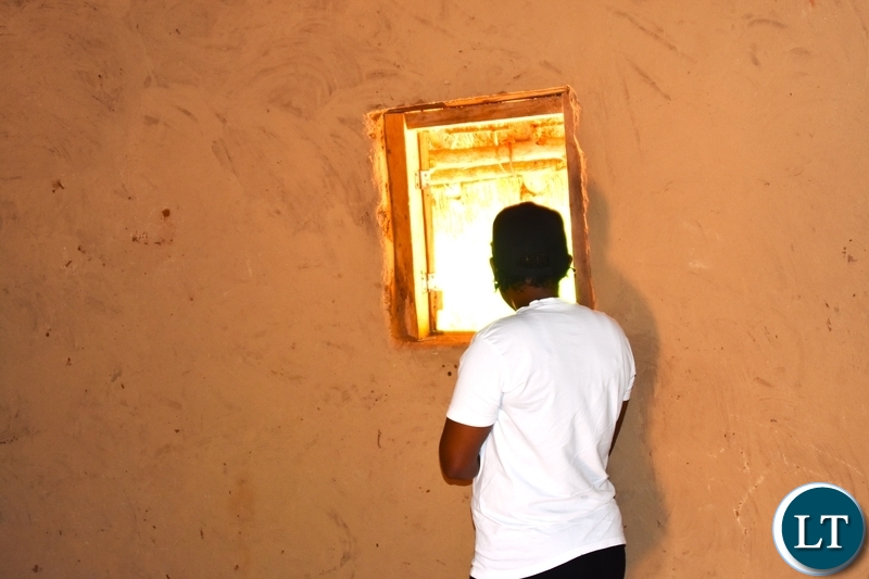 A young single woman romantically in love stares through the hut window as she and her romantic lover spend time alone together when he is visiting during courtship.
